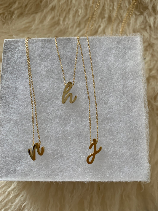 gold necklace with lowercase cursive letter 